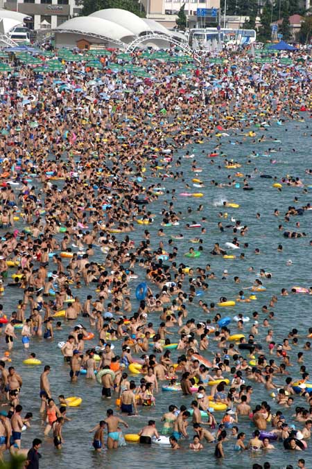 The NO.1 Bathing Beach in east China's Shandong Province is packed with visitors Saturday, July 22, 2006. With the arrival of a travel season, bathing beaches in the city have become a hot cake with tourists. [Xinhua]