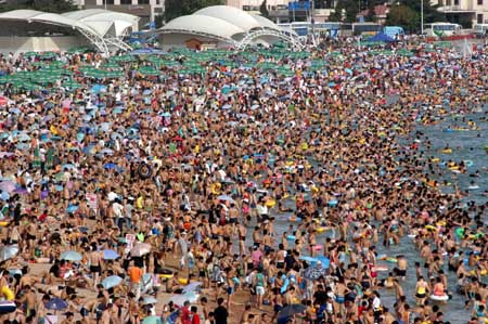 The NO.1 Bathing Beach in east China's Shandong Province is packed with visitors Saturday, July 22, 2006. With the arrival of a travel season, bathing beaches in the city have become a hot cake with tourists. [Xinhua]
