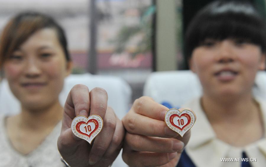 Citizens show emblems to mark the 10th World Blood Donor Day as donating blood in a mobile blood collection vehicle in Lin'an, east China's Zhejiang Province, June 14, 2013.