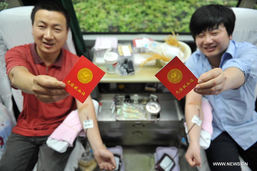 Citizens show their certificates as donating blood in a mobile blood collection vehicle in Lin'an, east China's Zhejiang Province, June 14, 2013, on the occasion of the World Blood Donor Day.