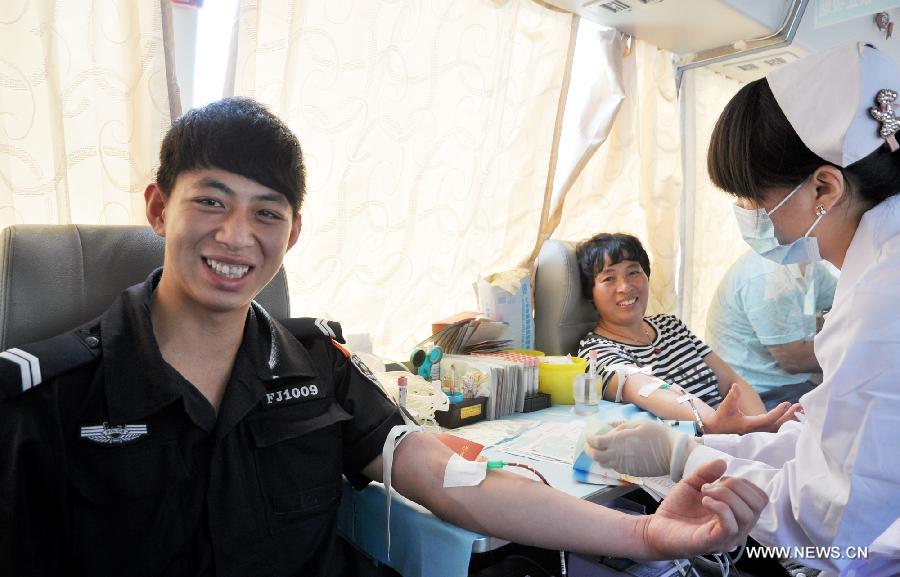 Citizens donate blood in a mobile blood collection vehicle in Handan City, north China's Hebei Province, June 14, 2013, on the occasion of the World Blood Donor Day.